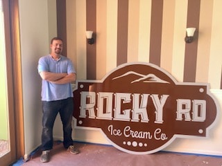 Paul standing next to the large Rocky RD Ice Cream Co. sign